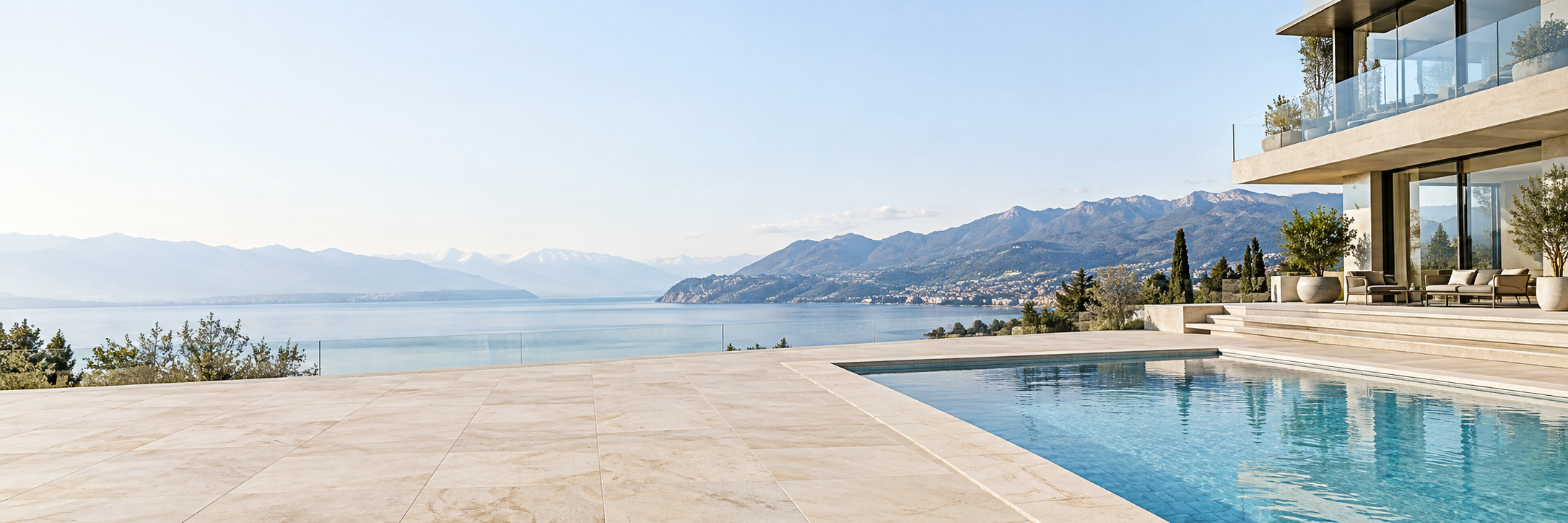 Terrasse dallée, marches et balcon d’une villa au bord du lac, avec piscine et margelles en pierre claire.