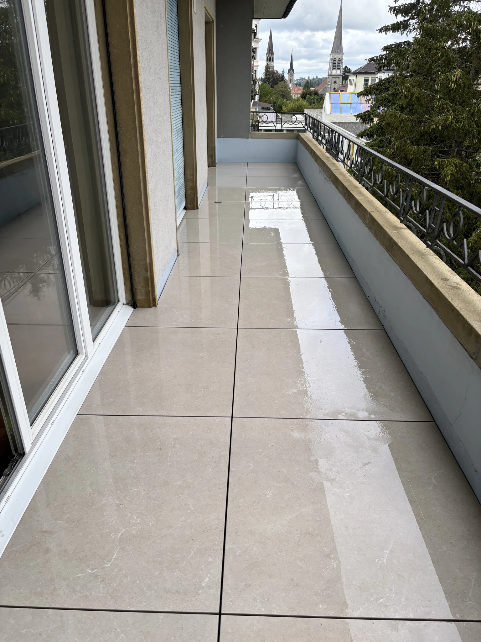 Vue depuis l’autre extrémité du balcon montrant les dalles beige clair le long de la façade